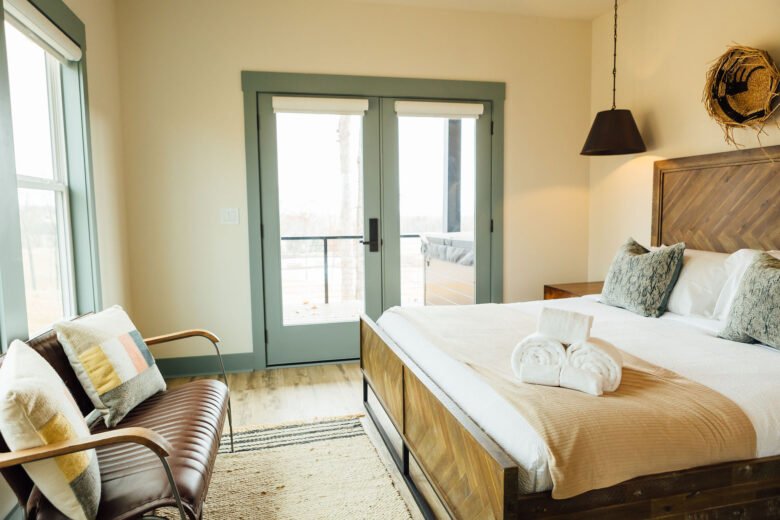 Bright bedroom with a white bed, green trim, and natural light from a large window