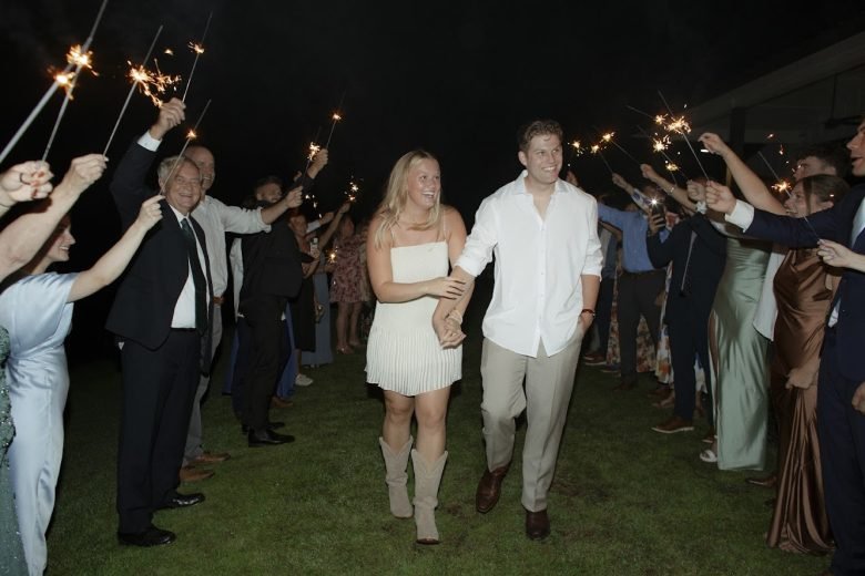 Newlywed couple walking through a sparkler sendoff at night