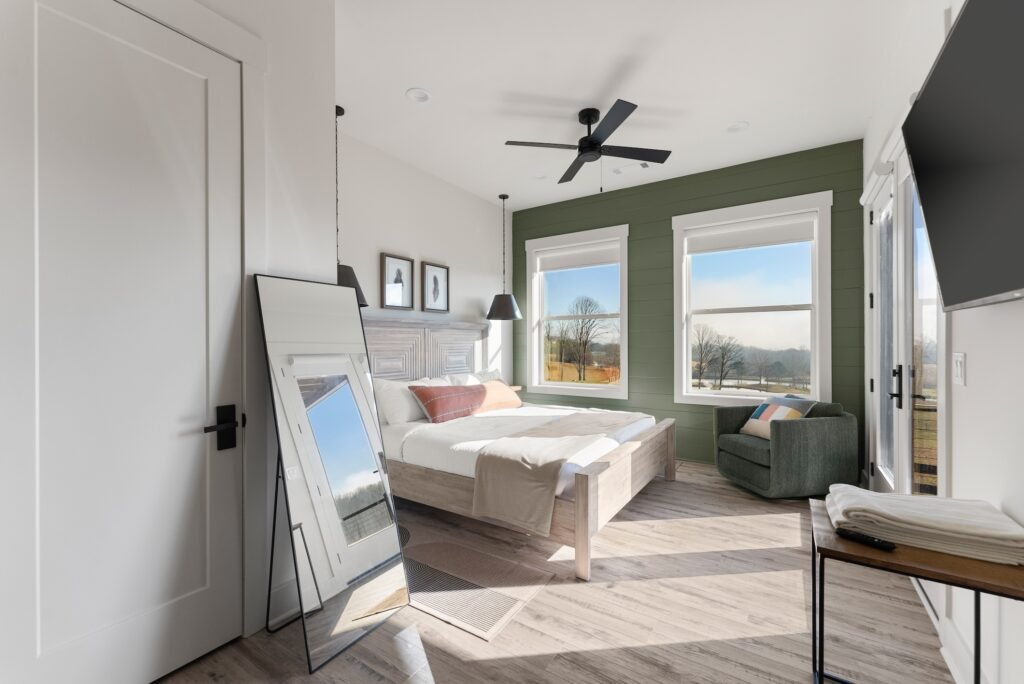 Bright ground-level guest room at Tatanka Overlook with a bed, ceiling fan, and mountain-view windows