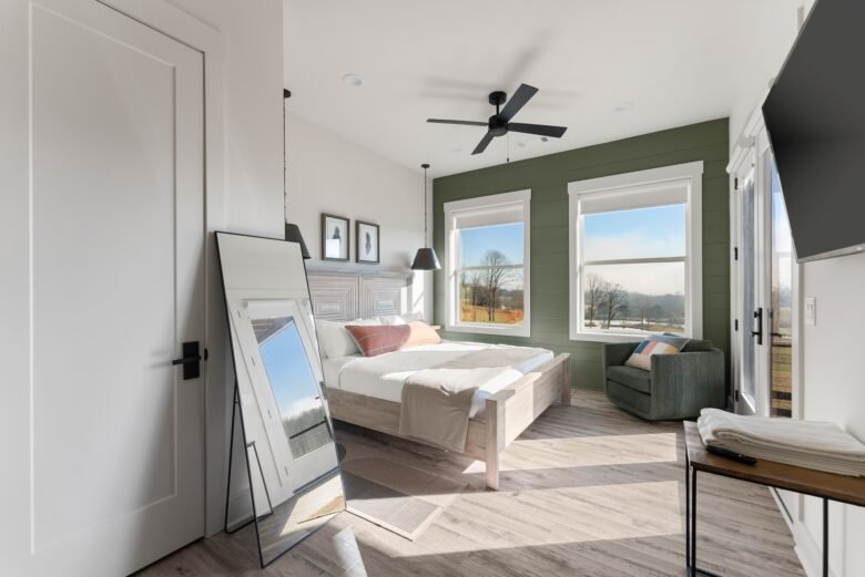 Bright ground-level guest room at Tatanka Overlook with a bed, ceiling fan, and mountain-view windows