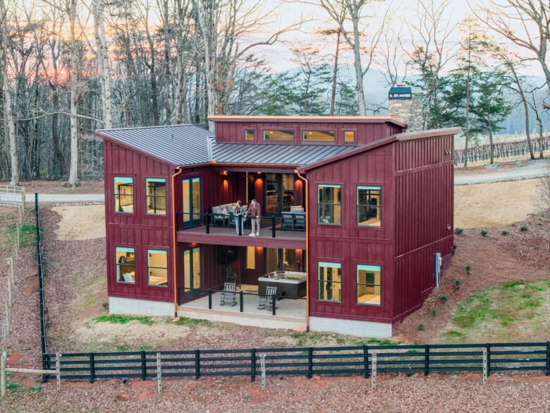 Sunset Lodge Sets modern red cabin with rooftop deck and large windows in a wooded setting