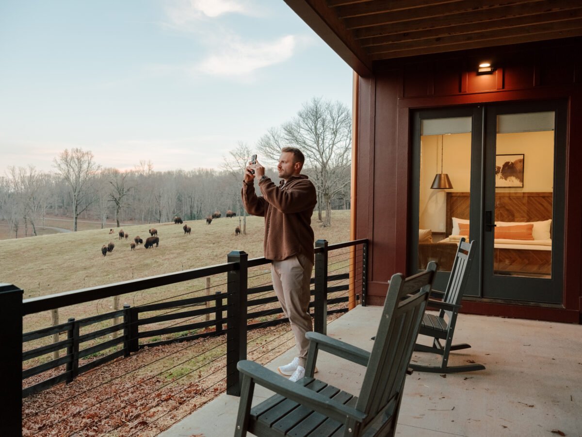 Couple standing on a lodge deck at KC Bison Ranch watching a bison herd graze in the North Georgia mountains